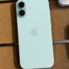 iPhone 16 verde agua fondo madera